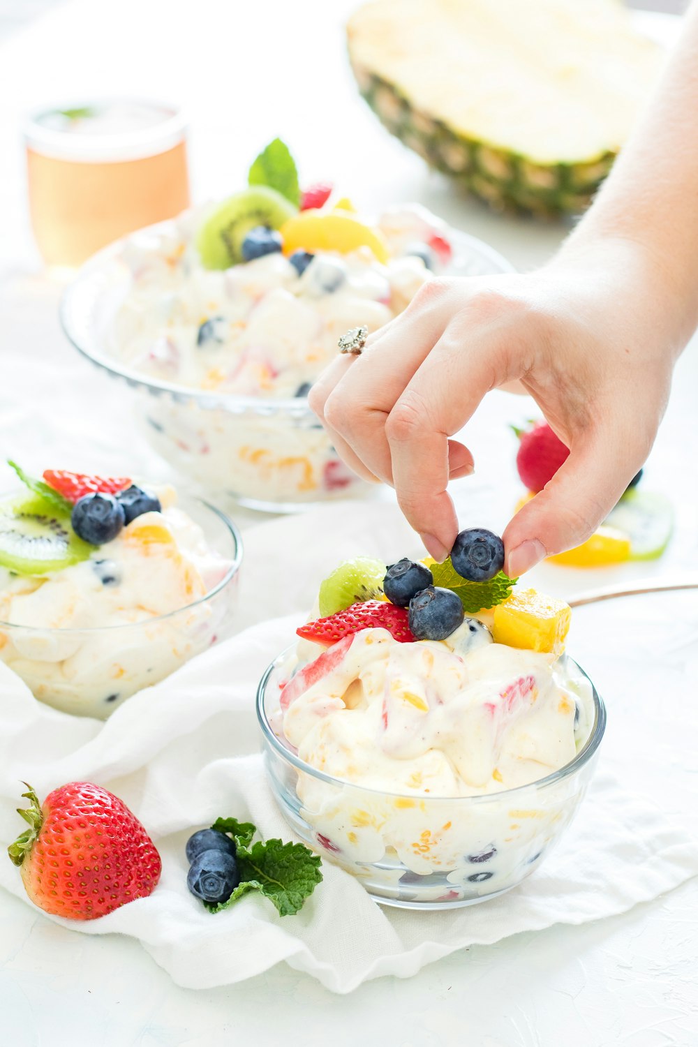 person holding blueberry fruit with hands on top of fruit salad