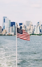 U.S.A. flag on pole near sea under cloudy sky