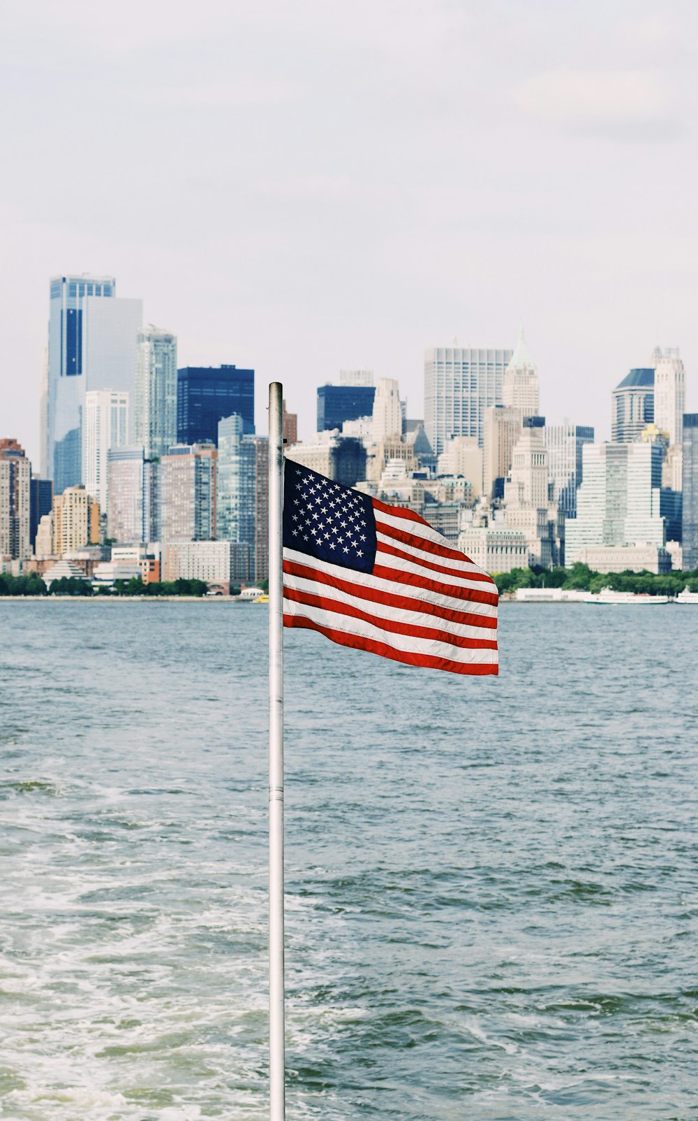 Drapeau des États-Unis sur le mât près de la mer sous un ciel nuageux