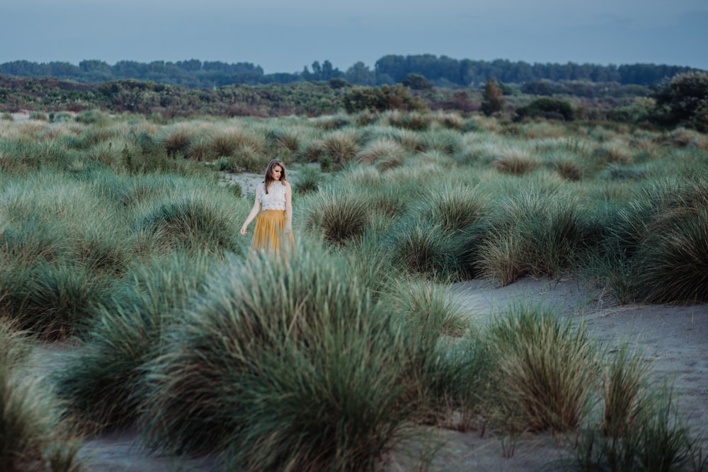 woman standing on gray soil surrounded by bush