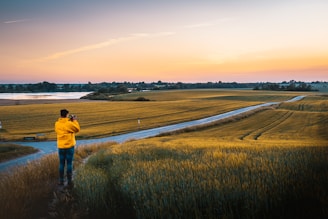 A filmmaker capturing a scenic rural landscape in the Cantal region during golden hour.