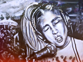 A black and white mural depicts a person with closed eyes singing passionately into a microphone. The person wears headphones and has light-colored hair. The background includes a crowd of people, suggesting a concert or performance setting. The image is artistically stylized, creating a dramatic and energetic atmosphere.