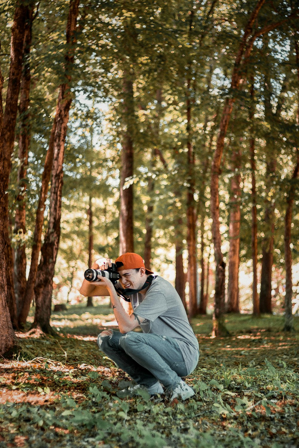 man sitting while taking photo near tree
