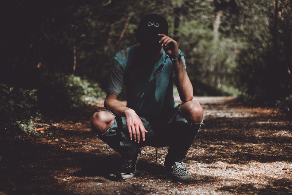 hombre sosteniendo la gorra en el camino cerca de los árboles