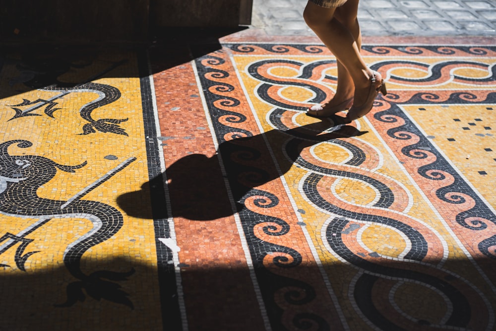 person standing on orange, yellow, and black tiled surface