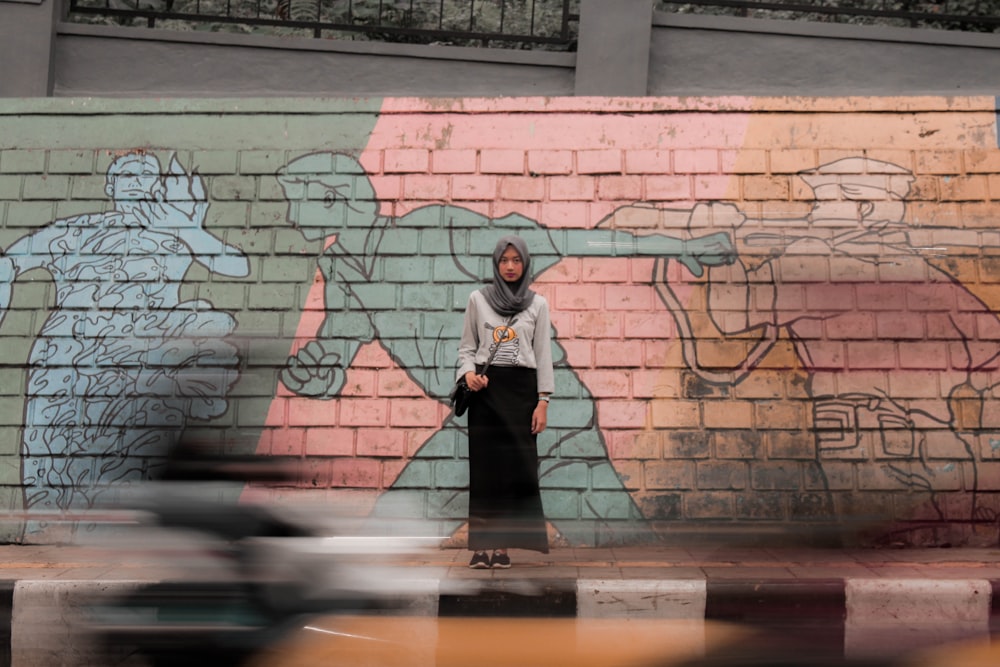 woman standing against mural wall