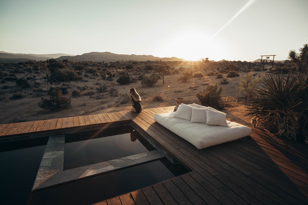 white mattress and pillows on wooden flooring near swimming pool