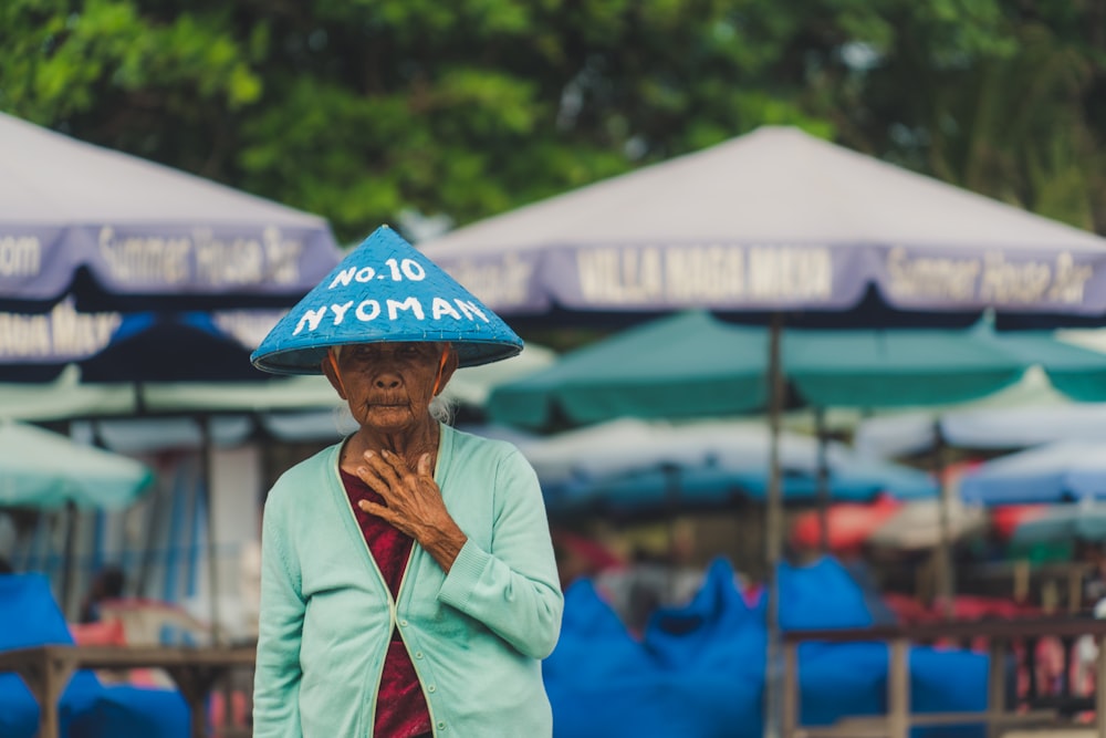 Mujer con sombrero azul cerca de sombrillas de patio púrpuras