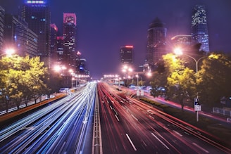 time-lapse photography of cars passing on road between buildings