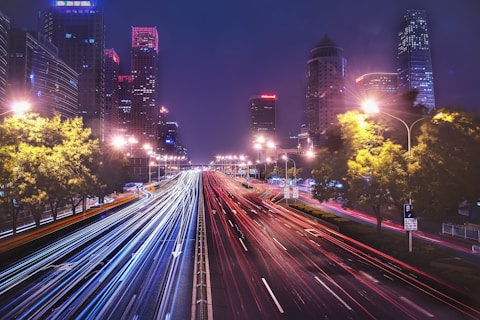time-lapse photography of cars passing on road between buildings