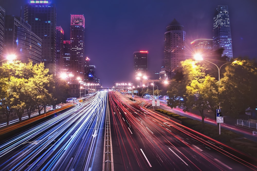 time-lapse photography of cars passing on road between buildings