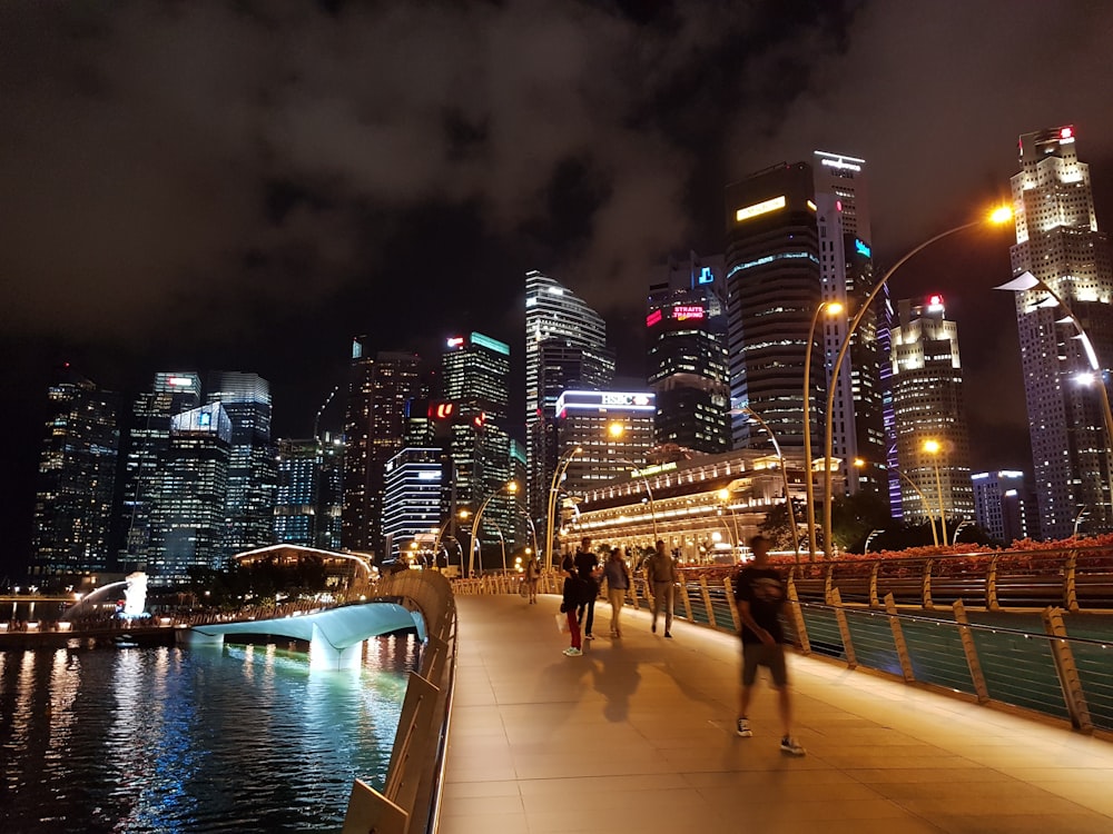 people walking on bridge over body of water during nighttime