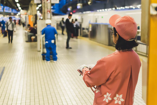 back of woman wearing fitted cap standing in train station