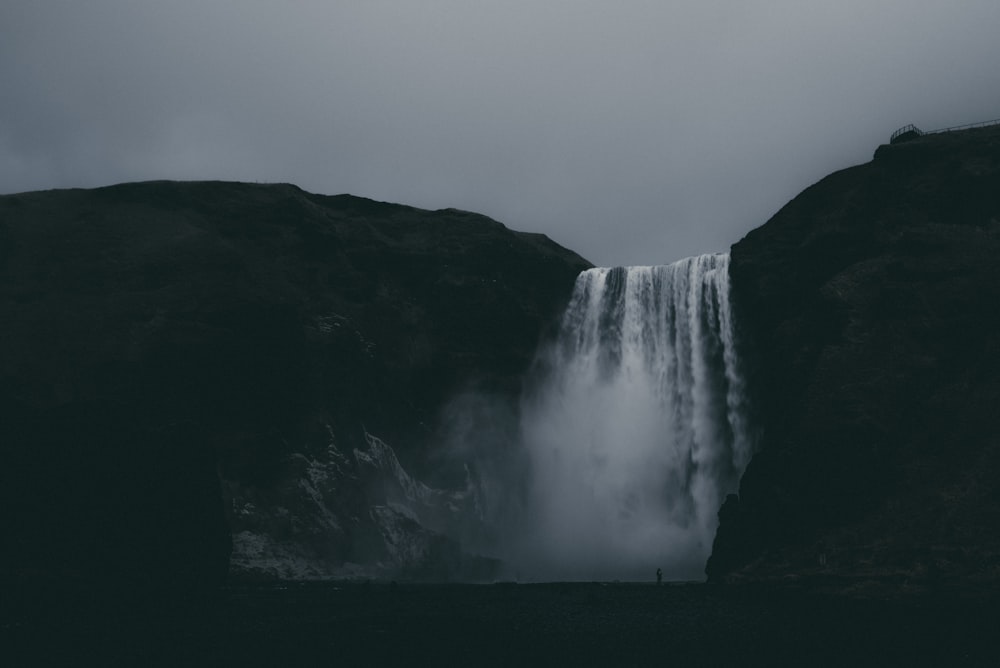 low-angle photography of waterfalls under cloudy sky