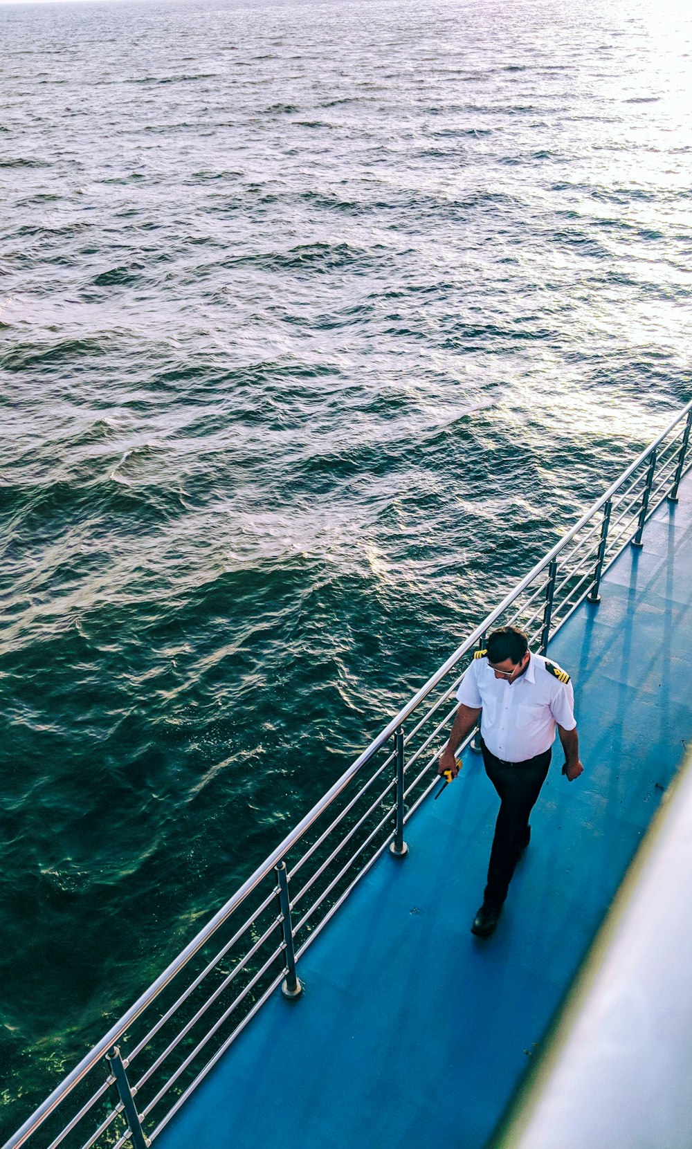 uomo che cammina sulla superficie blu della barca