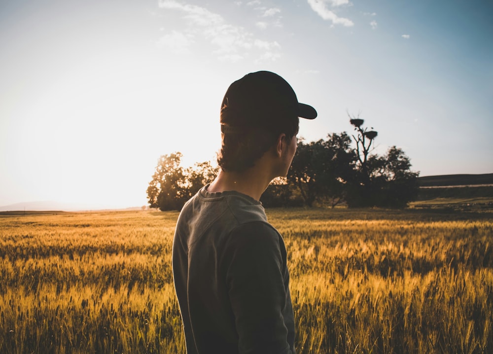 man with fitted cap facing brown grass field