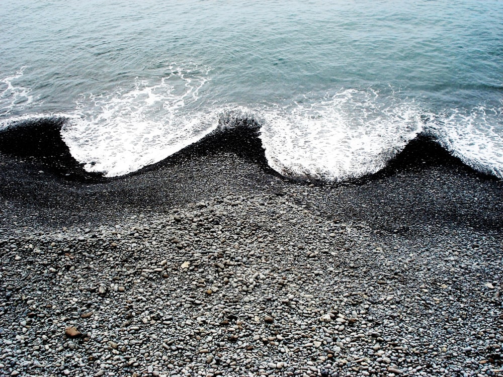 Meereswellen schmiegen sich an schwarzen Strandsand