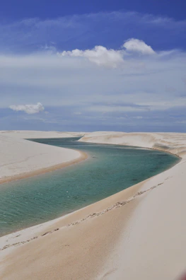 A breathtaking turquoise lagoon nestled between white sand dunes under a bright blue sky.