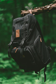 A sturdy 30-50L backpack resting against a tree in a forest