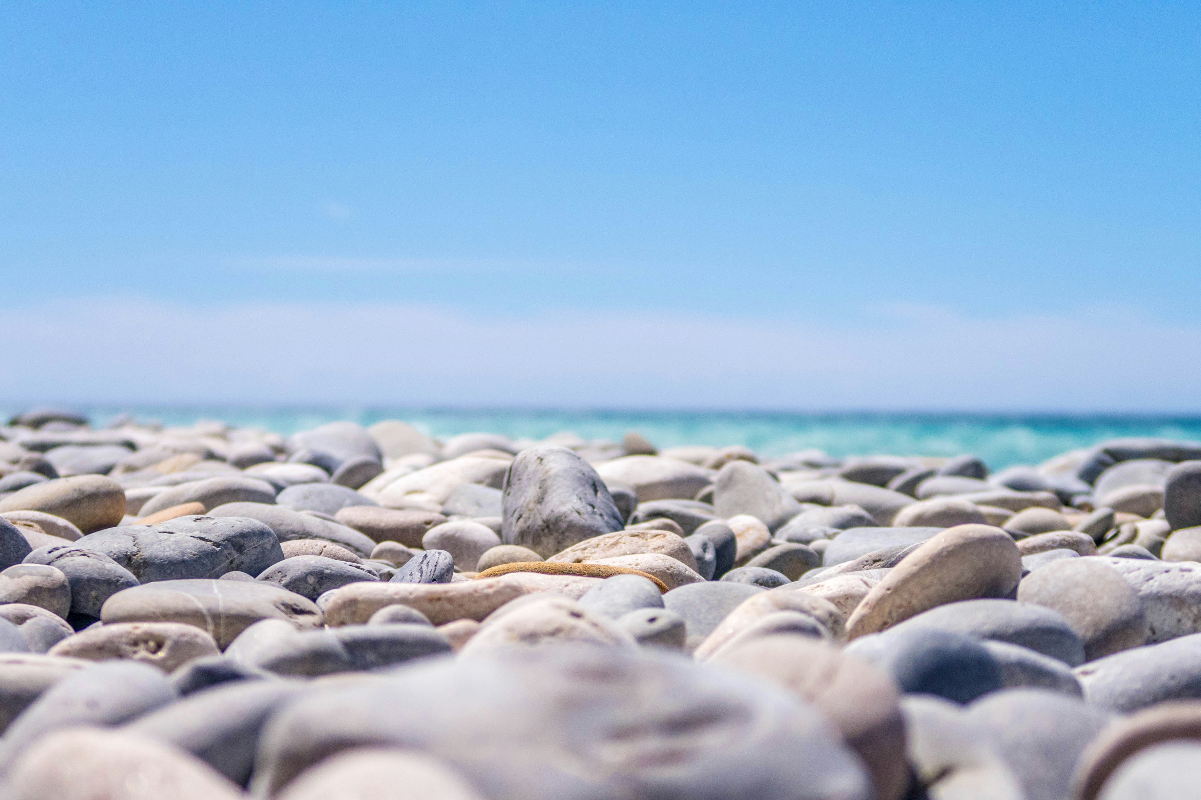 pietre su una spiaggia assolata e il mare calmo, uno dei panorami da ammirare durante le vacanze dell'estate durante uno dei viaggi da non perdere