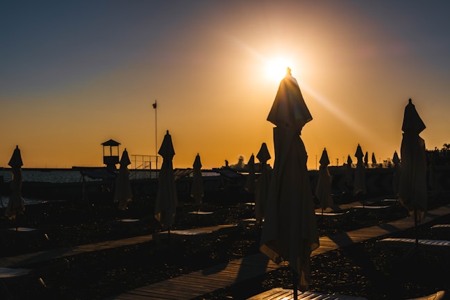 Sunset view with Madtre umbrellas casting long shadows on the shore.