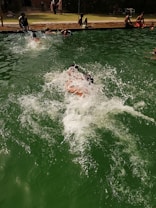 A group of students enjoying a swimming lesson with an instructor in a sunny outdoor pool.