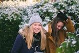 two woman smiling while walking near plants