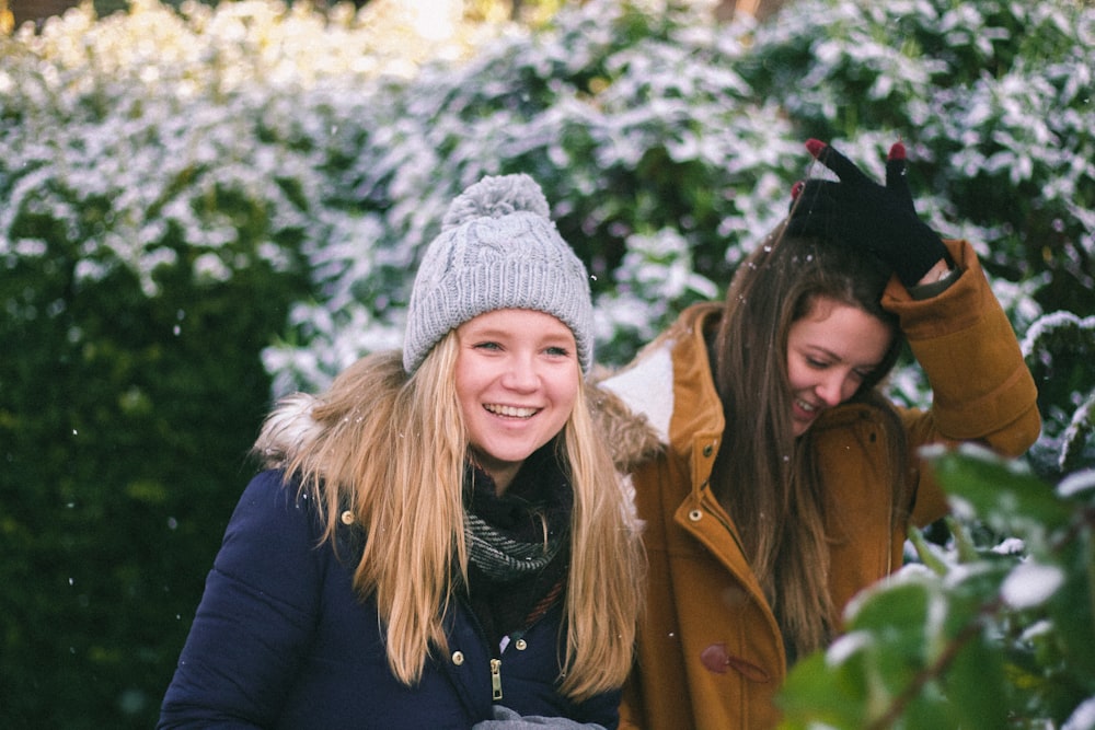 two woman smiling while walking near plants