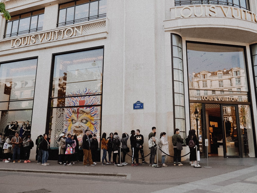 pessoas na fila ao lado da loja Louis Vuitton