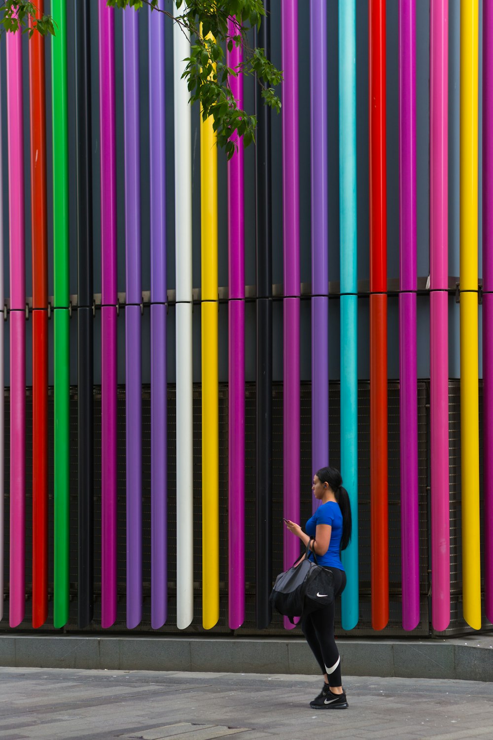昼間、色とりどりの建物の壁のそばに立つ女性