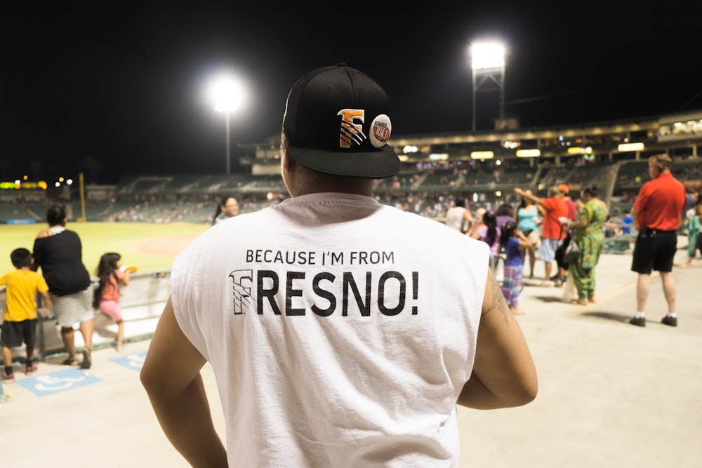 Homem vestindo boné preto assistindo esporte dentro da quadra