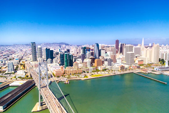 A vibrant illustration of a bridge made of financial symbols linking two cityscapes.