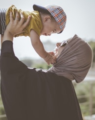 woman holding boy during daytime