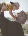 woman holding boy during daytime