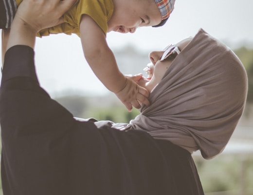 woman holding boy during daytime