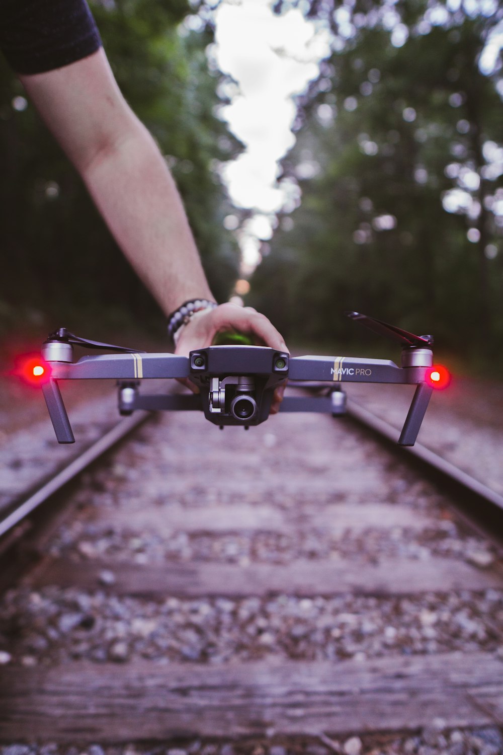 personne tenant un drone quadricoptère noir et rouge