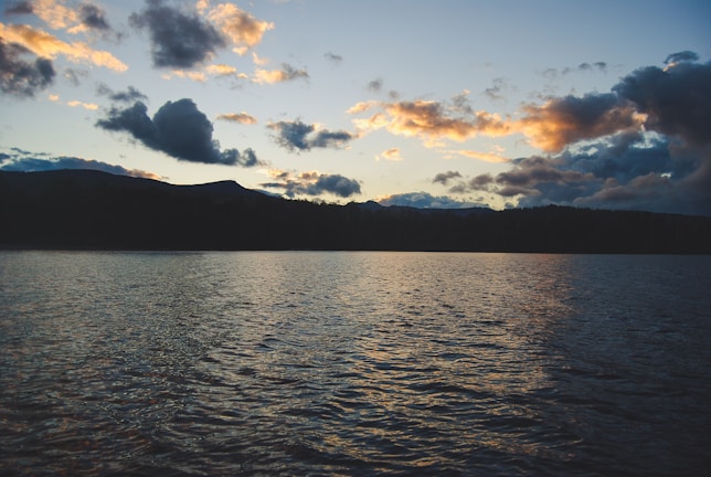 A serene lake reflecting the surrounding mountains at sunset.