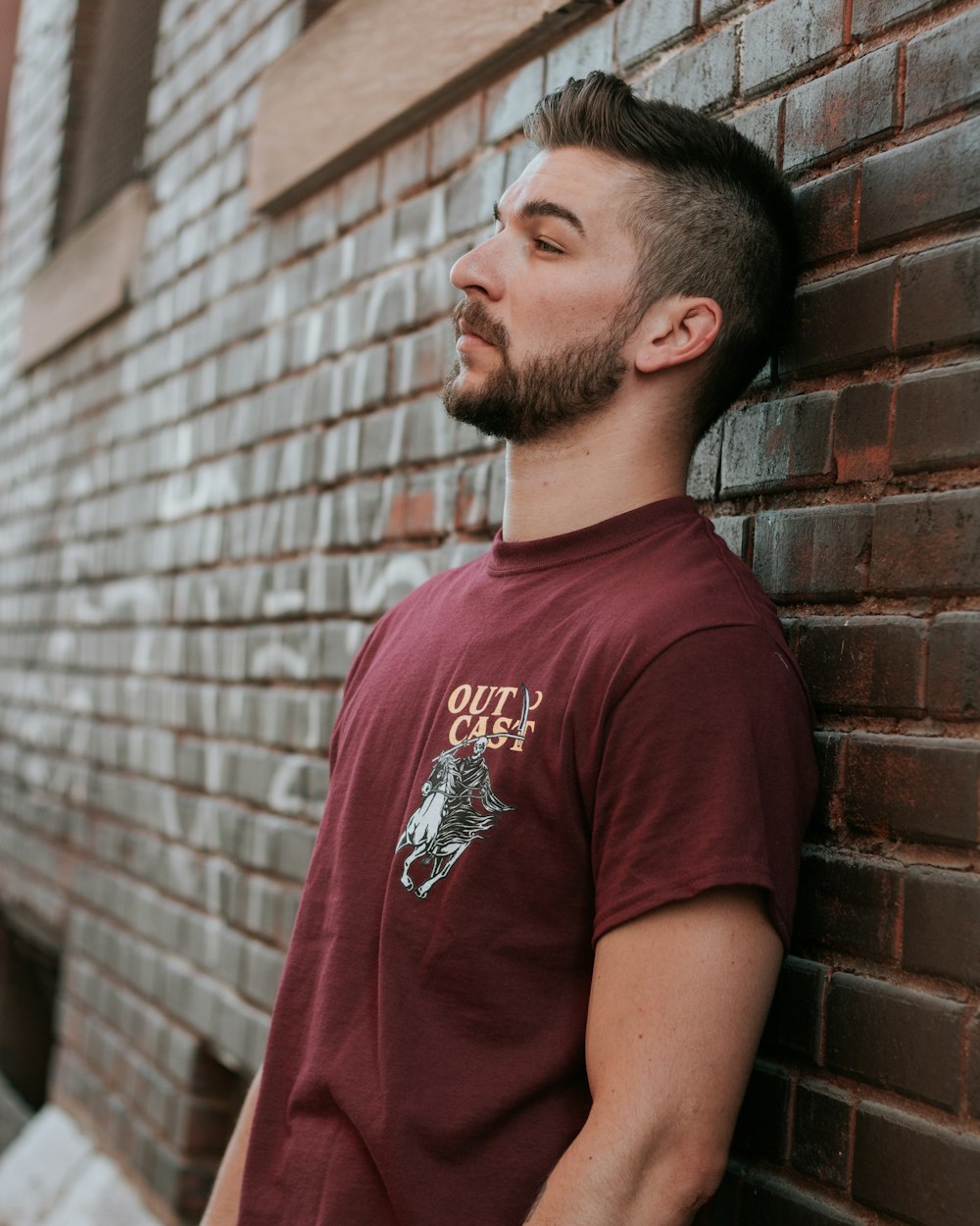 man leaning against brick wall