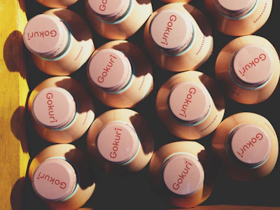 Top view of multiple detox juice bottles lined up on a sleek black surface with subtle pink accents.