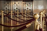 Rows of elegant velvet ropes with golden stanchions create a sense of sophistication and grandeur, likely in an upscale venue or event space. The floor reflects light, adding to the luxurious atmosphere.