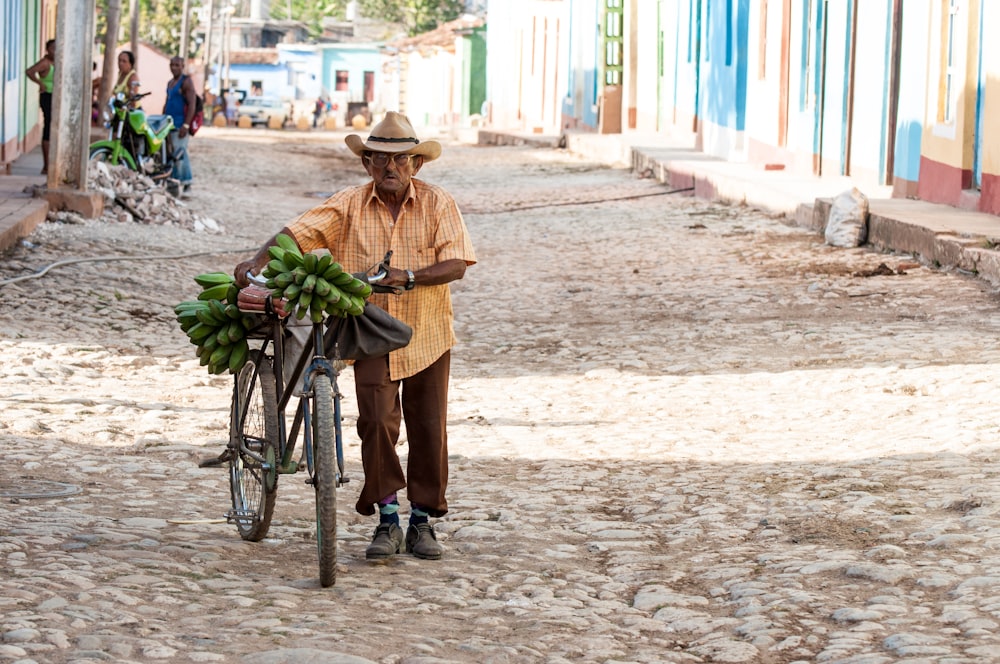 Hombre que camina en la pasarela mientras sostiene su bicicleta