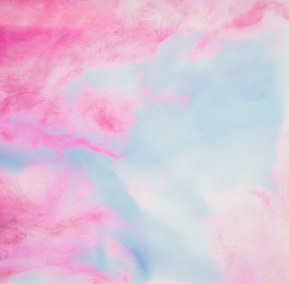 a pink and blue background with clouds in the sky