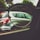 A pair of eyeglasses held up to a car window, focusing on the car outside. The lens frames the vehicle, highlighting the contrast between the lens-focused sharpness and the blurred surroundings.