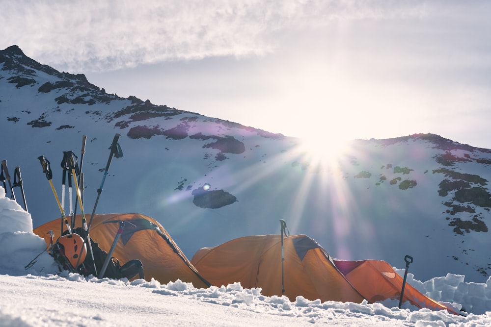 Trois tentes dôme jaunes et rouges sur une montagne enneigée