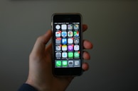 Close-up of a hand holding a smartphone showing the alarm activation app.