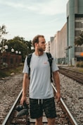 man standing on train rail at daytime