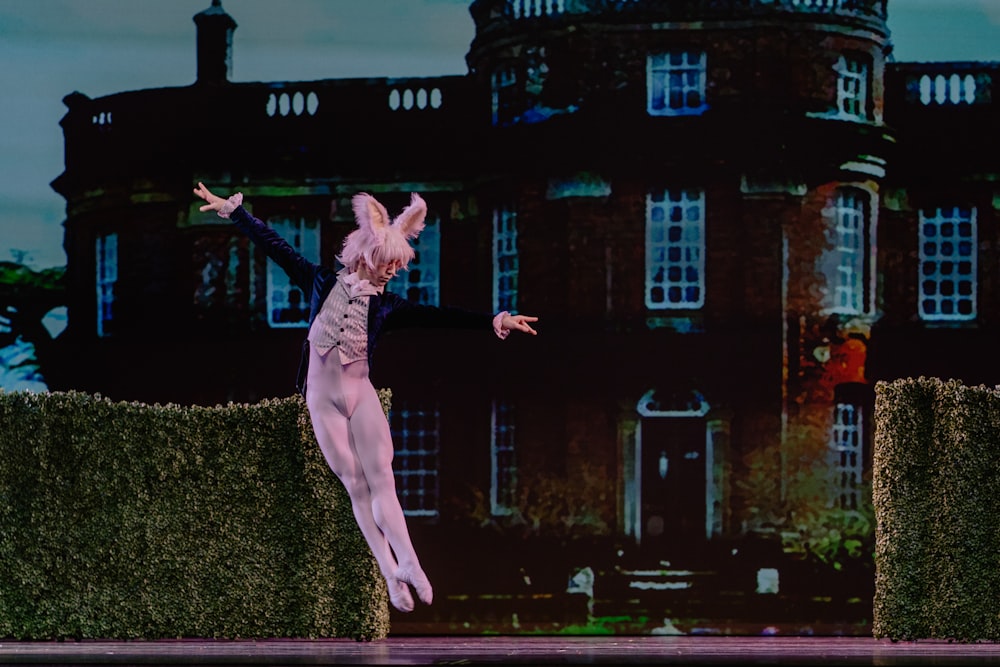 man wearing rabbit costume jumping near the green grass wall