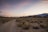 A cyclist riding through the Sahara desert with a stunning sunset in the background.