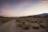A cyclist riding through the Sahara desert with a stunning sunset in the background.