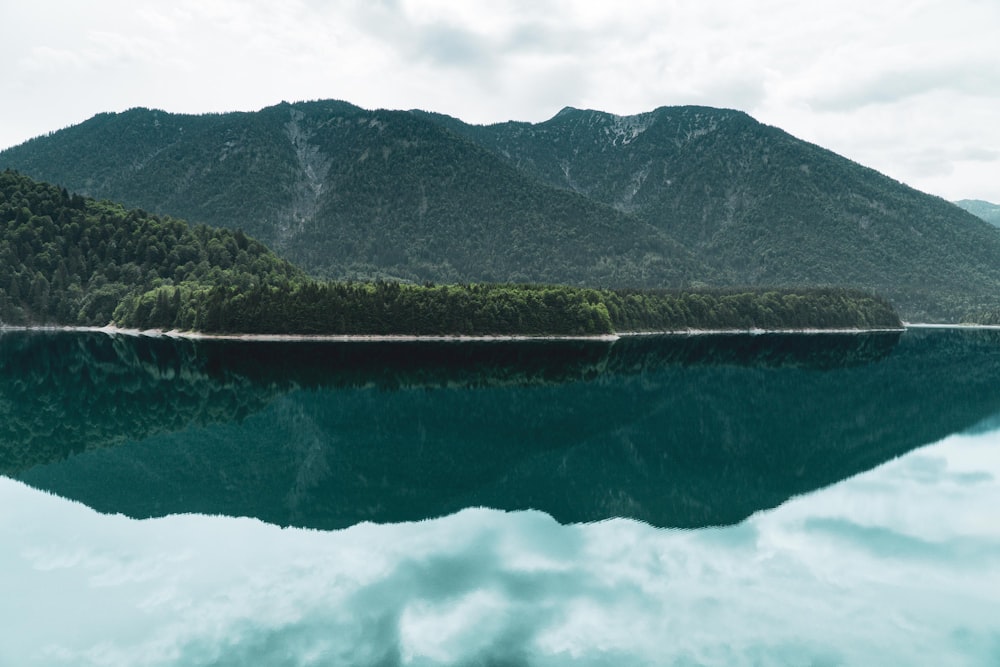 calm body of water near mountain